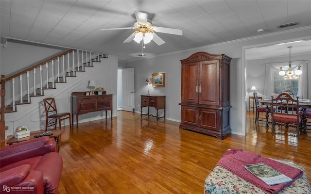 living area with stairs, visible vents, wood finished floors, and ornamental molding