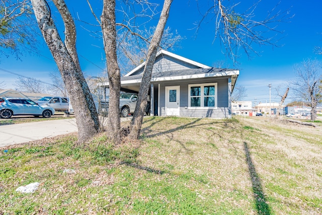 bungalow-style house with an attached carport, concrete driveway, and a front yard