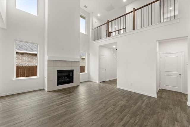 279 Bright Alcove Ct, Lavon, TX 75166 - unfurnished living room with a high ceiling, healthy amount of natural light, dark wood-type flooring, baseboards, and a tile fireplace