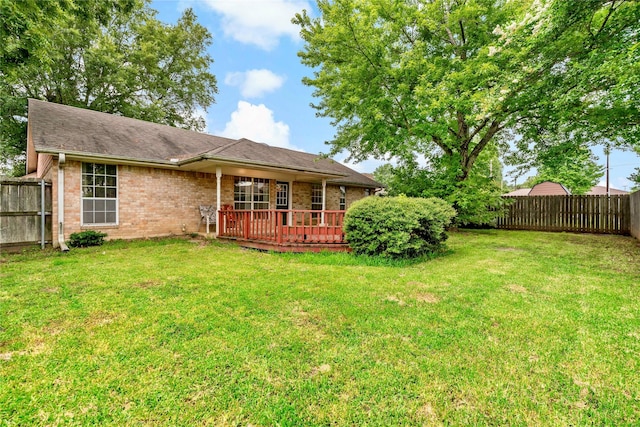 exterior space with brick siding, a fenced backyard, a wooden deck, and a yard