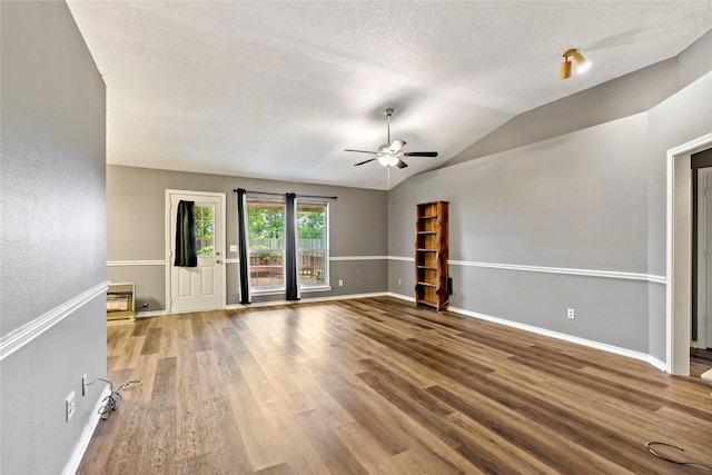 unfurnished room featuring a textured ceiling, baseboards, vaulted ceiling, and wood finished floors