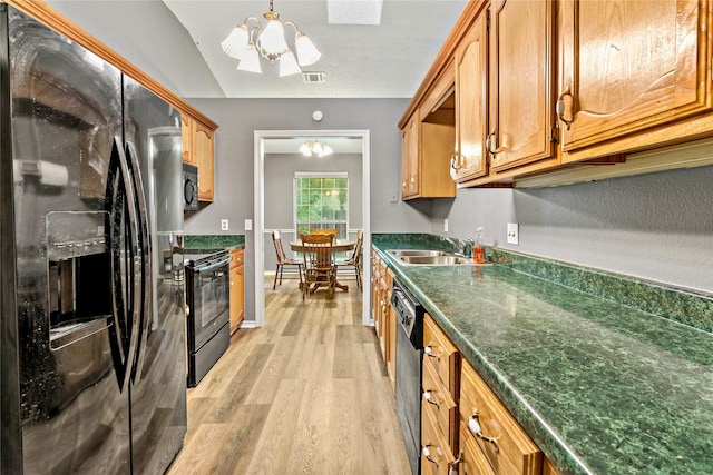 kitchen with a notable chandelier, dark countertops, light wood-style floors, a sink, and black appliances