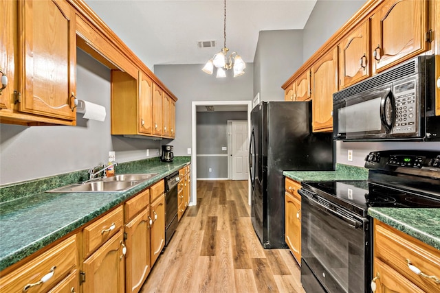 kitchen featuring light wood finished floors, dark countertops, visible vents, a sink, and black appliances