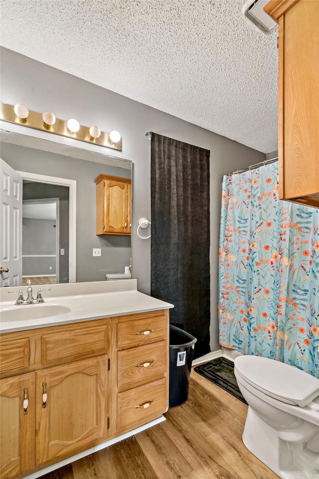 bathroom featuring a textured ceiling, vanity, wood finished floors, and toilet