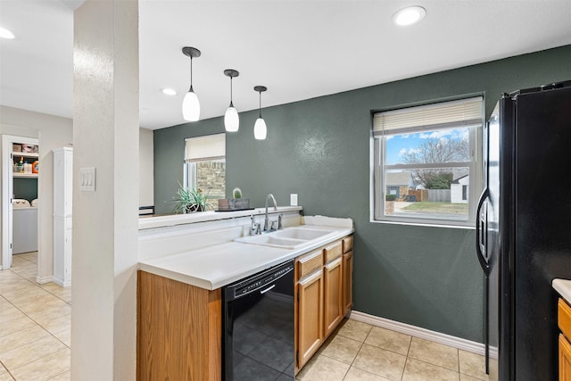 kitchen featuring decorative light fixtures, light countertops, a healthy amount of sunlight, black appliances, and a sink