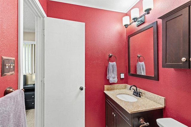 half bathroom featuring a textured wall, vanity, and toilet