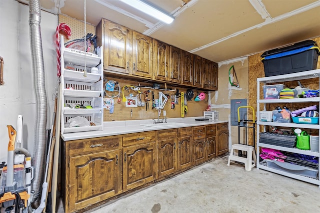 kitchen with brown cabinets, unfinished concrete flooring, light countertops, and a sink