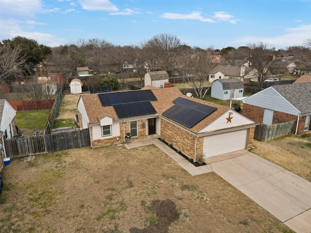 single story home featuring an outbuilding, fence private yard, roof mounted solar panels, a storage unit, and a front lawn