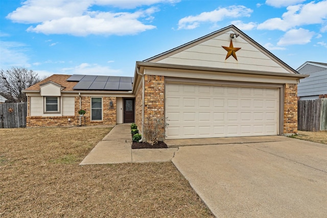 ranch-style house featuring concrete driveway, brick siding, fence, and roof mounted solar panels