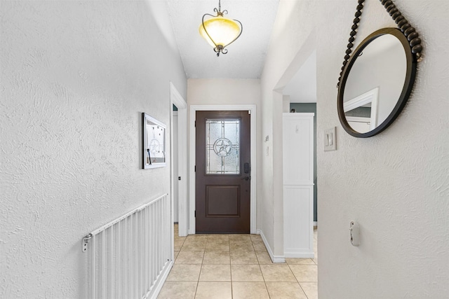 doorway to outside with light tile patterned floors and a textured wall