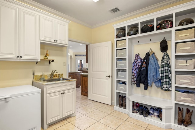 mudroom featuring light tile patterned floors, visible vents, arched walkways, ornamental molding, and a sink