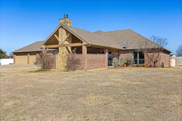 view of front of house with a shingled roof, a chimney, fence, a front lawn, and brick siding