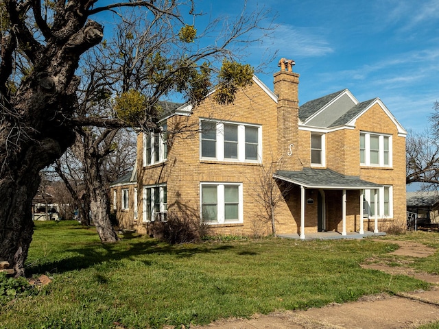 view of front of property with brick siding, a chimney, and a front lawn