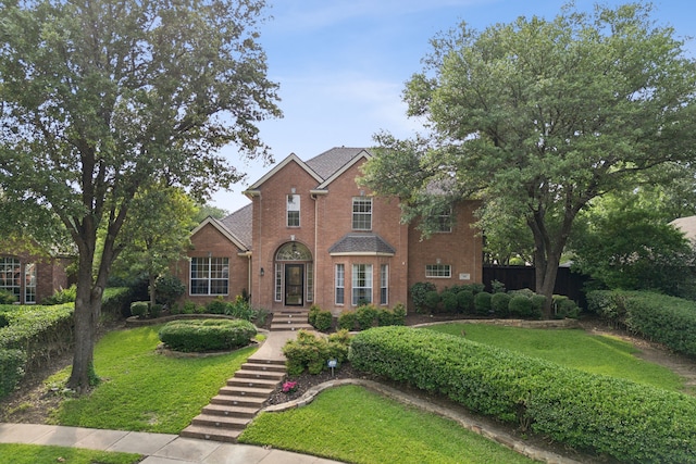 view of front of house with brick siding, a front lawn, and fence