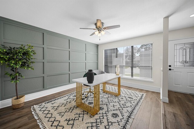 office with a decorative wall, baseboards, a ceiling fan, and wood finished floors