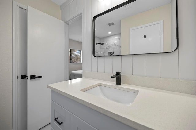 full bathroom with visible vents, tiled shower, and vanity