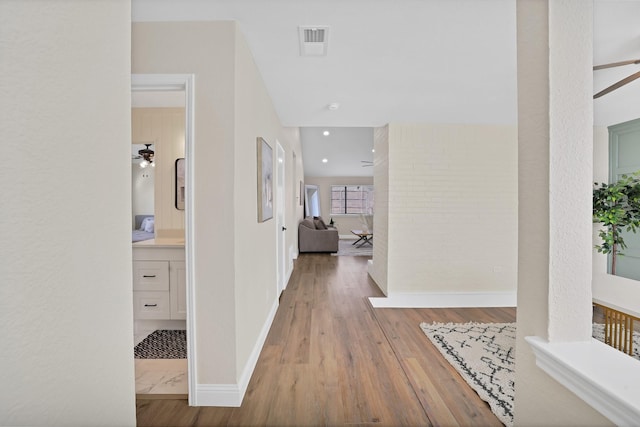 corridor with visible vents, baseboards, and wood finished floors