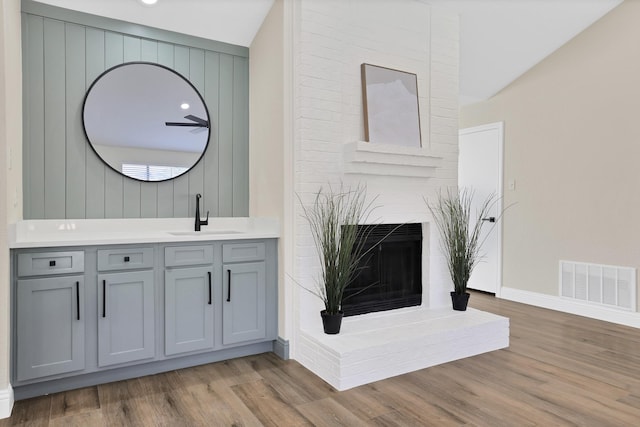 bathroom featuring visible vents, a fireplace, vanity, and wood finished floors