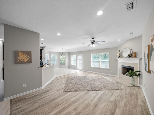 living area with light wood-style floors, a tile fireplace, visible vents, and baseboards