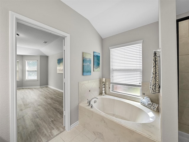 full bathroom with visible vents, baseboards, a garden tub, tile patterned flooring, and vaulted ceiling