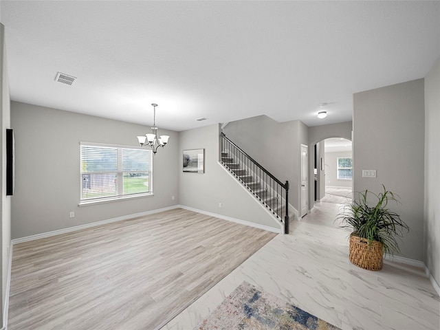 unfurnished room with arched walkways, visible vents, stairway, an inviting chandelier, and baseboards