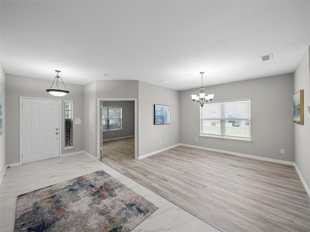 entryway with baseboards, marble finish floor, visible vents, and a notable chandelier