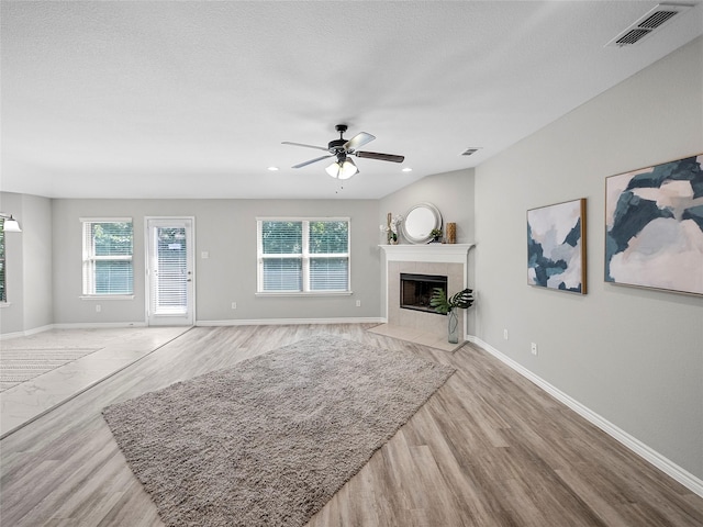 living room with baseboards, a tile fireplace, visible vents, and a healthy amount of sunlight