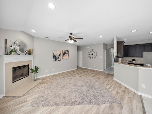 living room featuring light wood finished floors, baseboards, a fireplace, and visible vents