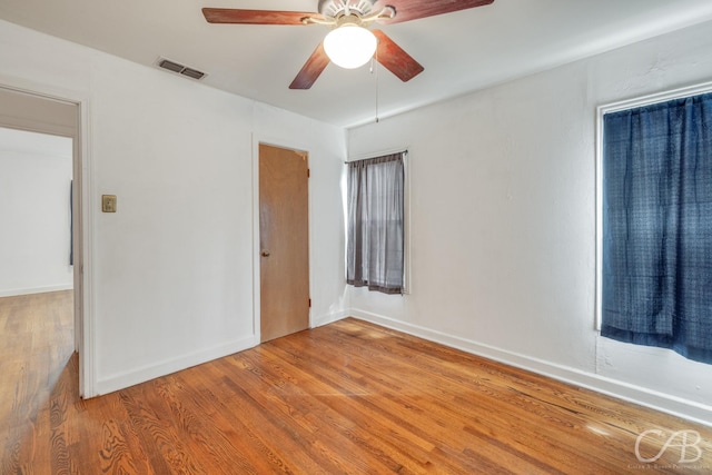 empty room featuring light wood-type flooring, baseboards, visible vents, and ceiling fan