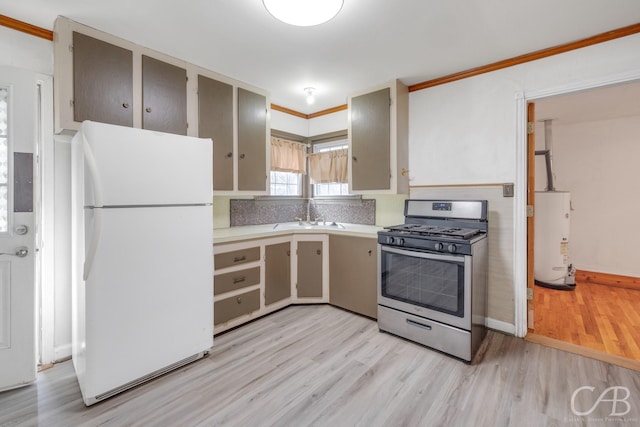 kitchen with gas water heater, light countertops, freestanding refrigerator, gas stove, and a sink