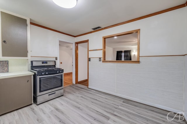 kitchen featuring light wood finished floors, visible vents, ornamental molding, light countertops, and stainless steel range with gas cooktop