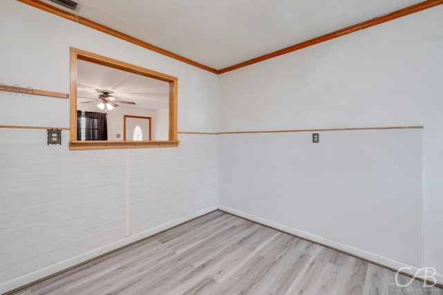 empty room with baseboards, visible vents, light wood-style flooring, and crown molding