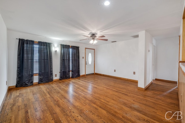 unfurnished room featuring a ceiling fan, wood finished floors, visible vents, and baseboards