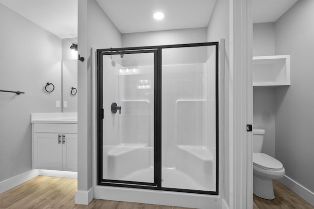 bathroom featuring vanity, a stall shower, wood finished floors, and toilet