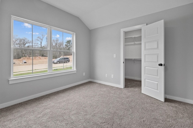 unfurnished bedroom with baseboards, lofted ceiling, carpet, a spacious closet, and a closet