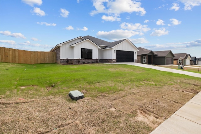 view of front of property featuring driveway, an attached garage, fence, a front lawn, and board and batten siding