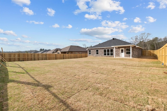 back of property with a yard, brick siding, and a fenced backyard