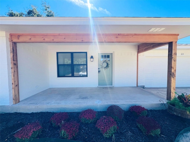 entrance to property featuring a garage and brick siding