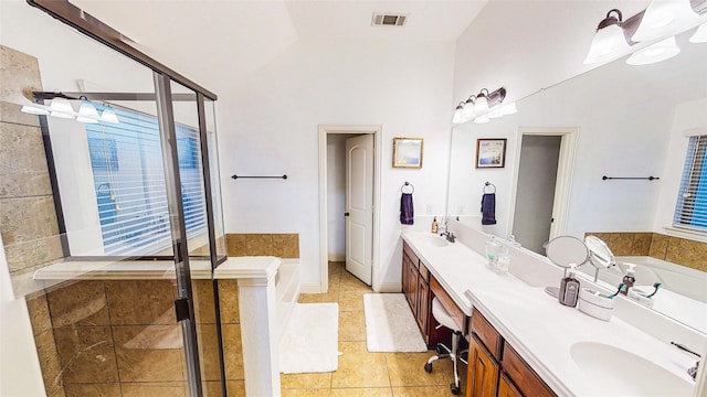 full bath with double vanity, a stall shower, a garden tub, vaulted ceiling, and a sink