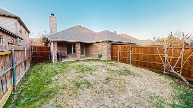 rear view of property featuring brick siding, a patio, a chimney, a shingled roof, and a fenced backyard