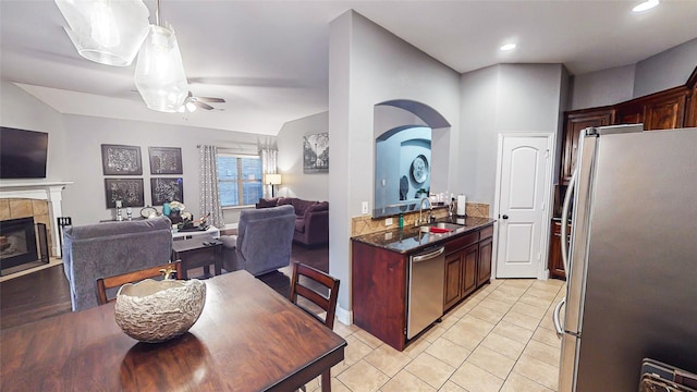 kitchen featuring light tile patterned floors, a tile fireplace, a sink, open floor plan, and appliances with stainless steel finishes