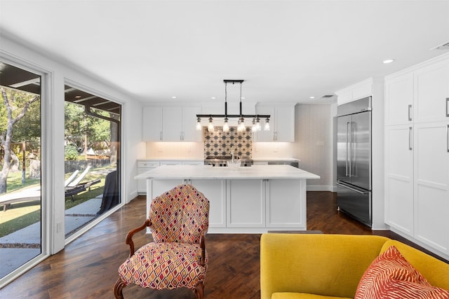 kitchen with white cabinets, a center island, stainless steel built in refrigerator, light countertops, and pendant lighting