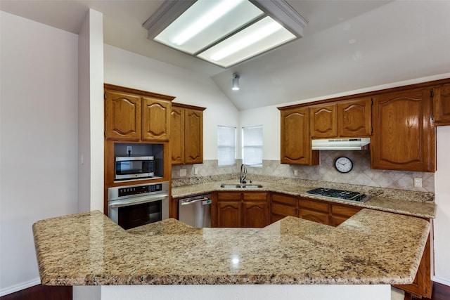 kitchen featuring brown cabinets, appliances with stainless steel finishes, a sink, and under cabinet range hood