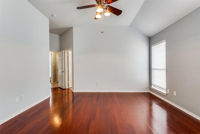 spare room featuring vaulted ceiling, ceiling fan, dark wood-style flooring, and baseboards