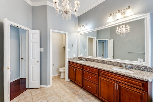 full bath featuring double vanity, toilet, ornamental molding, a sink, and a chandelier