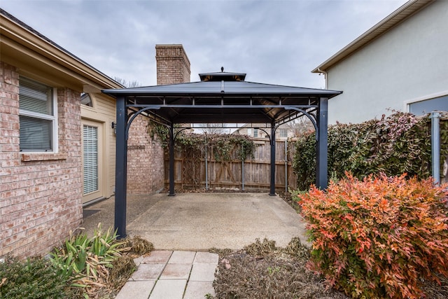 view of patio featuring a detached carport, fence, and a gazebo