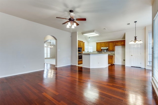 unfurnished living room featuring arched walkways, visible vents, a ceiling fan, baseboards, and dark wood finished floors