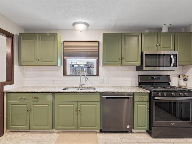 kitchen featuring a textured ceiling, a sink, light countertops, appliances with stainless steel finishes, and decorative backsplash