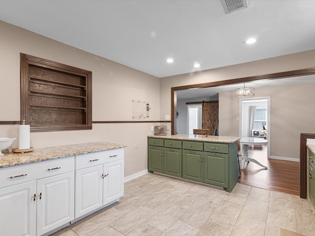 kitchen with pendant lighting, visible vents, a barn door, white cabinets, and green cabinetry