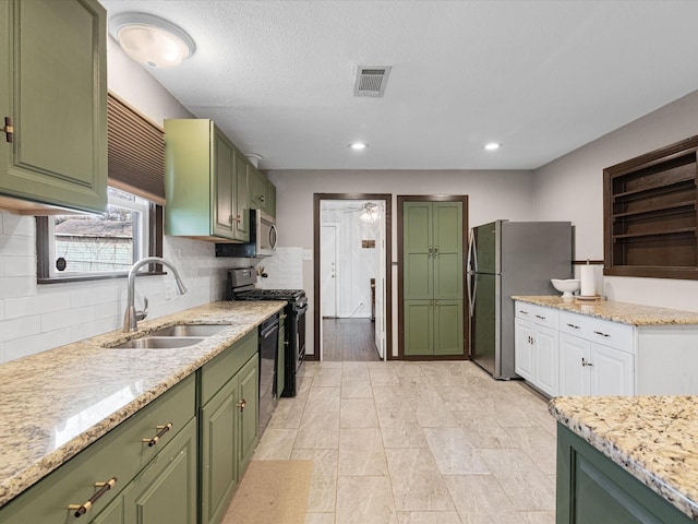 kitchen featuring stainless steel appliances, visible vents, backsplash, a sink, and green cabinetry